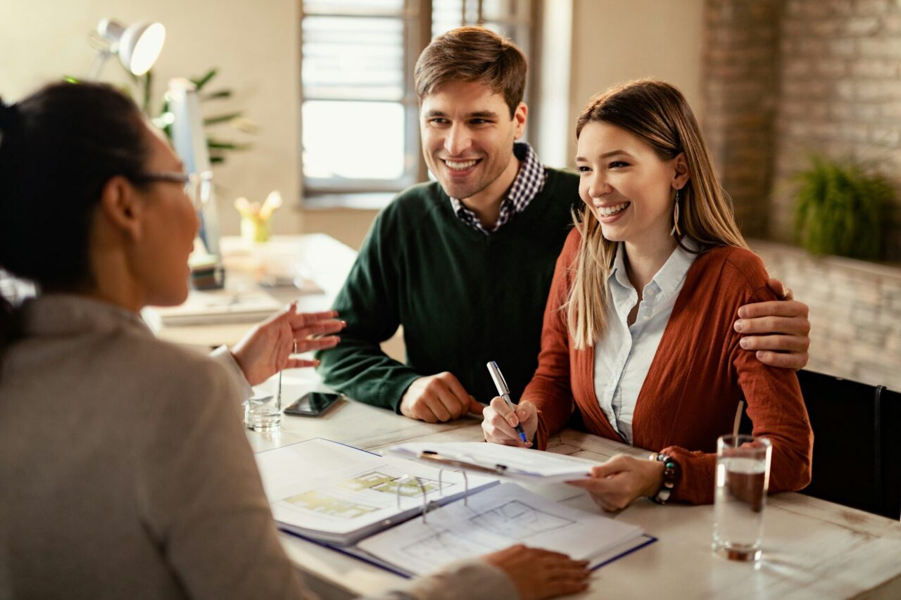 Primer Hogar happy-couple-signing-mortgage-contract-while-having-meeting-with-real-estate-agent-.jpg